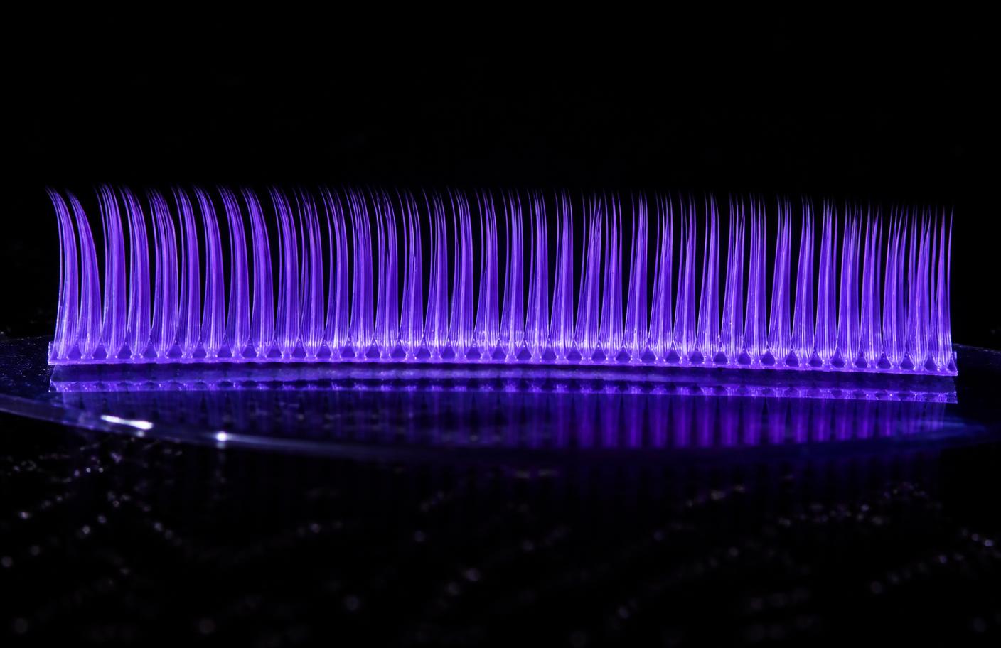 Fios sintéticos ultrafinos organizados em tela sob luz neon violeta